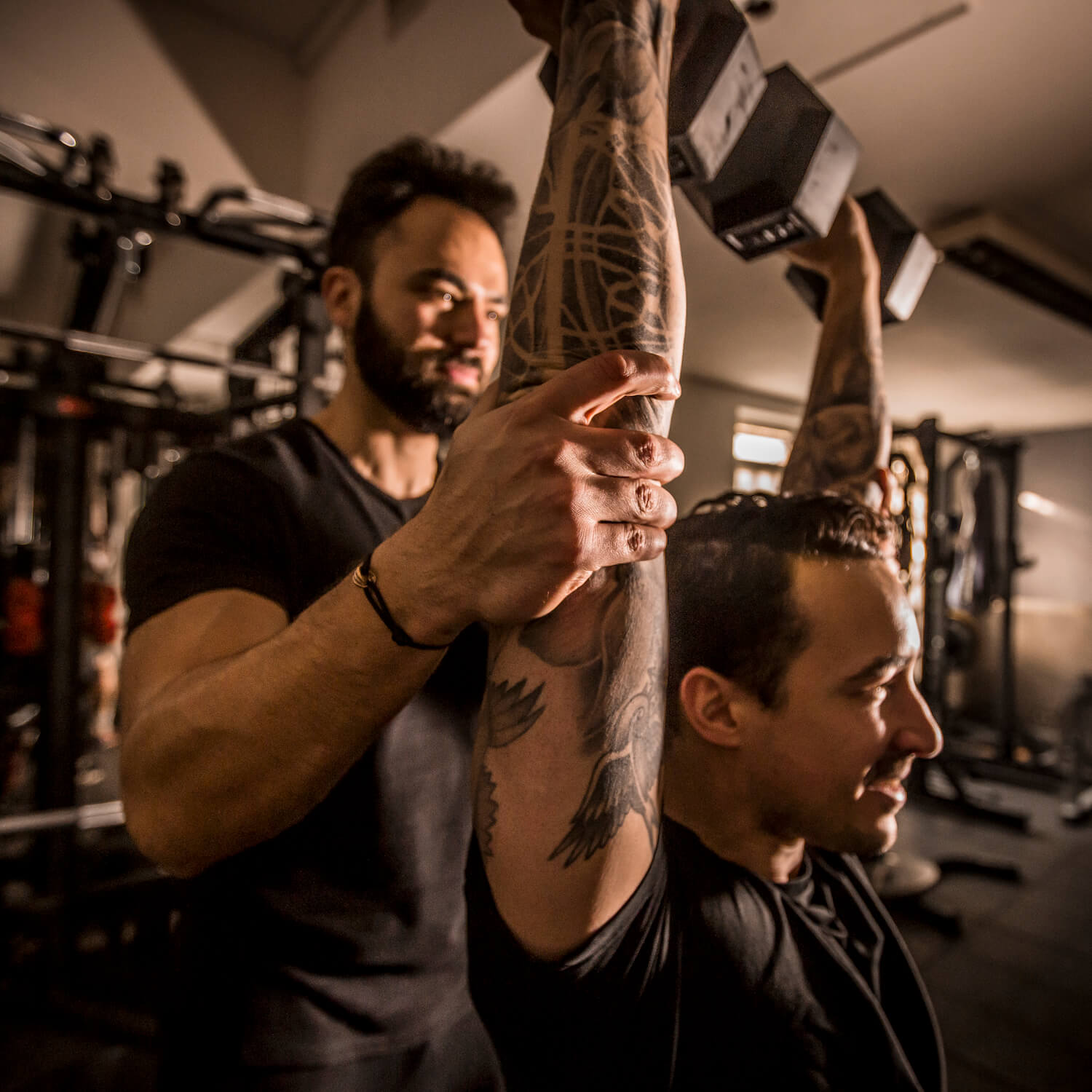 Bojidar helping a man lift weights as part of his health and fitness training